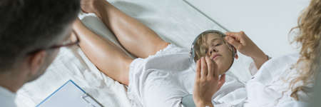 Therapist sitting close to the young woman keeping the small mirror both handsの写真素材