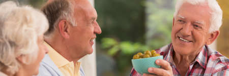Elder couple looking at their smiled senior friend