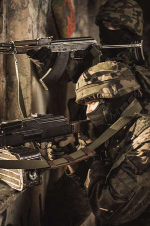 Uniformed soldiers pointing their guns ready to fire