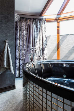 Bath with glassy walls in an unusual bathroom with old-fashioned curtain