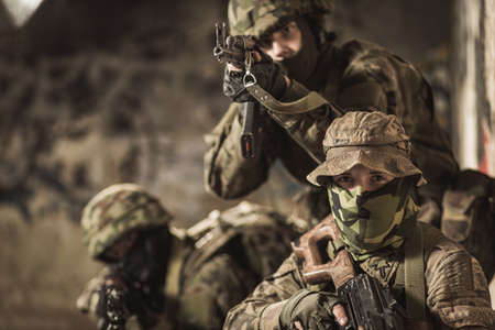 Photo of uniformed soldiers with guns ready to fireの写真素材