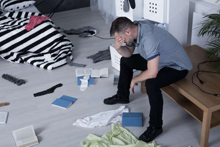 Despair man covering his face and his apartment after burglaryの写真素材