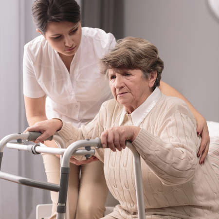 Photo of disabled elderly woman with zimmer having supportの写真素材