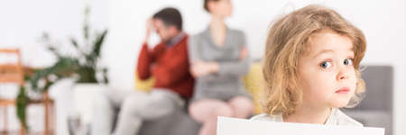 Sad boy looks surprised when his parents sitting offended at each other on the couchの写真素材