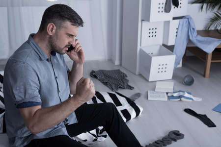 Angry man talking on phone and his house after burglary