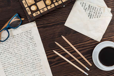 Wooden desktop with written notes, pencils and open letter envelope onの写真素材