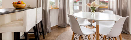 View of the kitchen island and a white dining table with chairsの写真素材