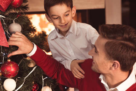 Happy father and son decorating Christmas treeの写真素材