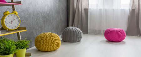 Shot of three colorful poufs in a grey roomの写真素材