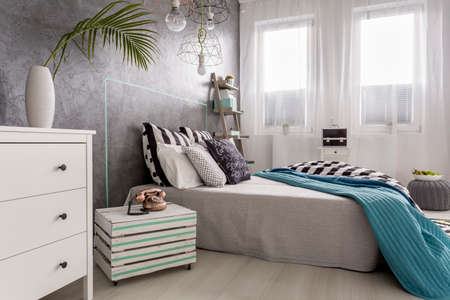 Shot of a bright bedroom with white chest of drawers and wooden nighstandの写真素材