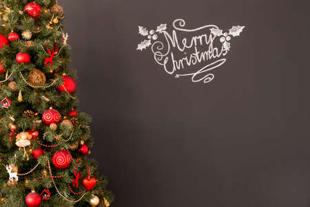 Red and gold Christmas tree beside a blackboard wallの写真素材