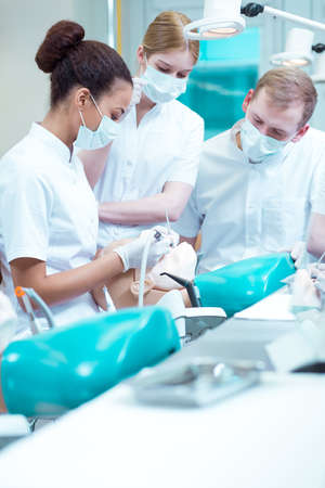 Female dentist showing something to her two stomatology studentsの写真素材