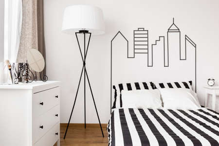 White commode and lamp in bright trendy bedroomの写真素材