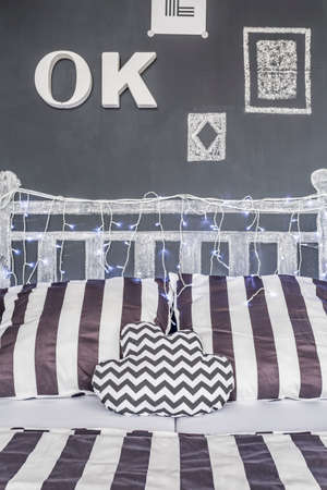 Shot of a bed and a chalkboard wall in a black and white bedroom