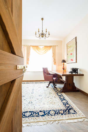 Classic home office interior with wooden desk and armchair