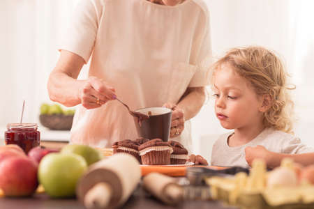 Young boy looking at the muffins made by his grandmaの写真素材