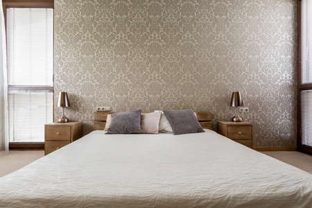 Light bedroom with decorative wallpaper and large double bed