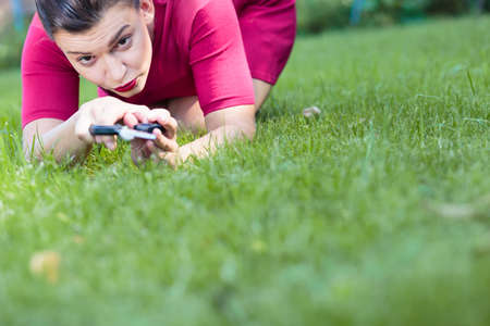 Beautiful woman cutting a grass using a scissors