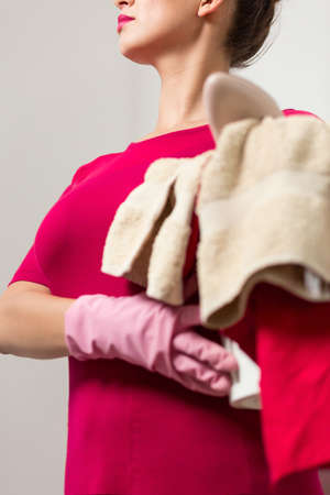 Shot of an elegant woman with laundry wearing cleaning glovesの写真素材