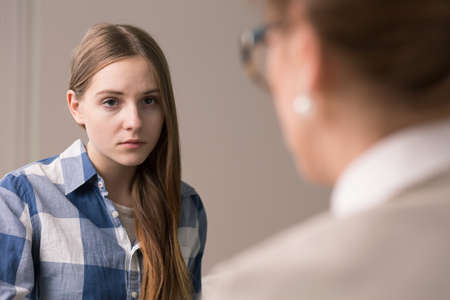 Sad and depressed teenager talking with psychologistの写真素材