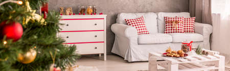 Bright room with comfortable sofa, decorated with Christmas treeの写真素材