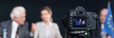 Close-up of camera recording businesspeople during press conference. Man talking with womanの写真素材