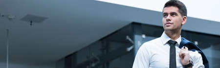 Young elegant businessman in white shirt and black tie leaving his officeの写真素材