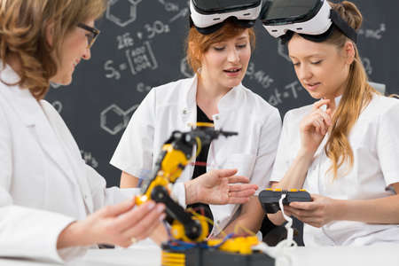 Shot of two students wearing virtual reality glasses and working in a classroom with their teacherの写真素材