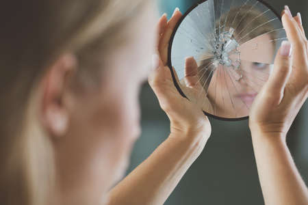 Woman with mental disorder holding small broken mirrorの写真素材
