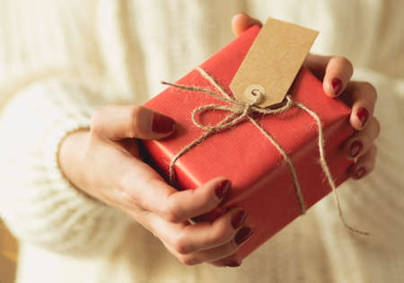 Close-up of woman holding christmas gift packed in red paper
