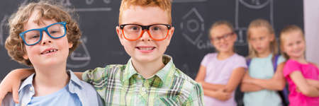 Happy school friends wearing new glasses, group of girls in the background, panoramaの写真素材
