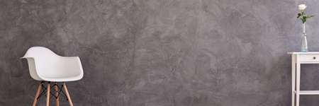 Concrete wall, a white armchair and a white night tableの写真素材