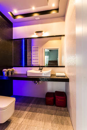 Bathroom with modern amenities, wide mirror and blue ceiling backlightの写真素材