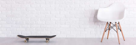 White brick wall, white modern armchair and skateboardの写真素材