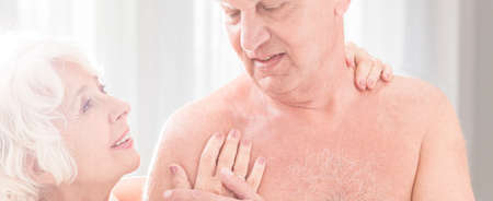 Elderly lady touching her naked husband's chest with happiness and passionの写真素材