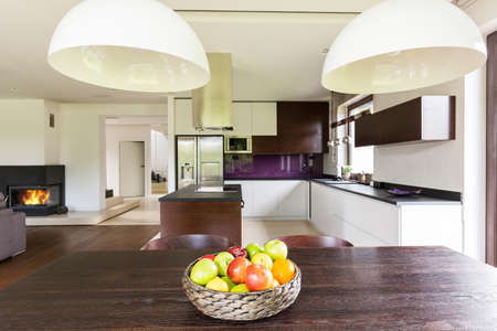 Dark wooden table with a straw fruit bowl in a stylish modern house