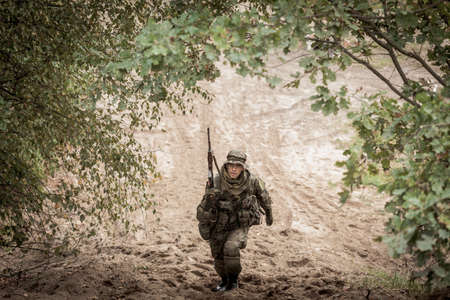 Male soldier with weapon in uniform during military maneuver on army training groundの写真素材