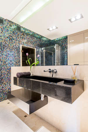 Modern bathroom with gleaming mosaic tiles and a large mirrorの写真素材