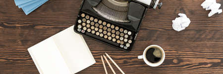 Top view of the desk with old typewriter, notebook, pencils and cup of black coffeeの写真素材