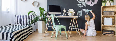 Modern creative studio interior and a woman painting on a chalkboard wallの写真素材