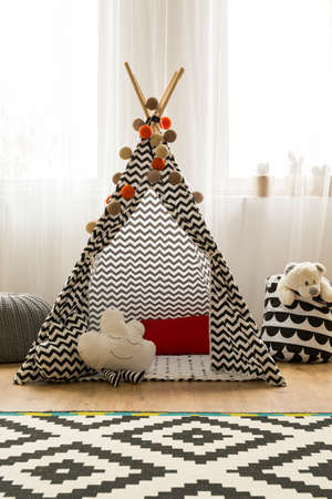 Patterned indian tent in a light monochromatic room in scandynavian style