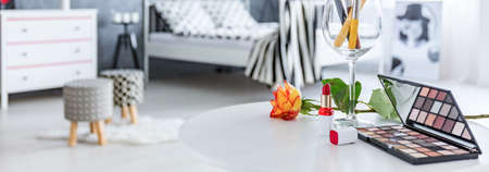 Cosmetics and rose lie on table  in bedroom