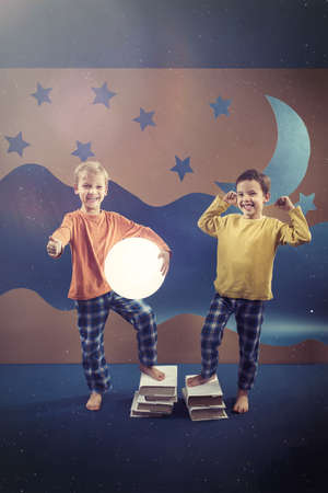 Happy small brothers wearing pajamas, night sky in backgroundの写真素材