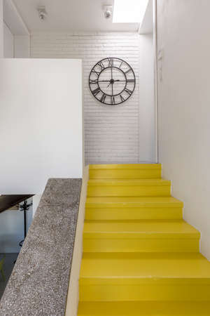 Staircase with yellow steps leading to corridor with huge clockの写真素材
