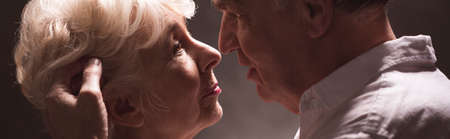 Senior man touching softly elderly woman in make-up on the hairの写真素材