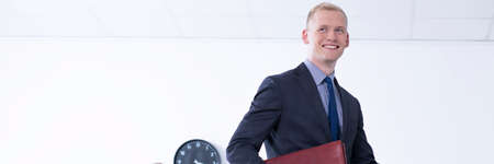 Smartly-dressed young businessman smiling in a bright office