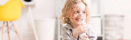 Smiling happy little boy using his inhaler in home