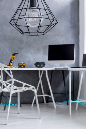 Shot of a grey home office with a big desk, a gap chair and a modern chandelierの写真素材