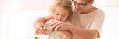Lovely close-up of a little boy with grandma, baking with hands dirty in flour