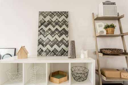 Close-up of decorations on white shelf next to stylish wooden shelf
